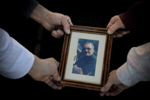 Quattro mani sorreggono una fotografia incorniciata