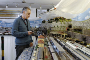 Alfredo Burani davanti a una stazione ferroviaria in miniatura.