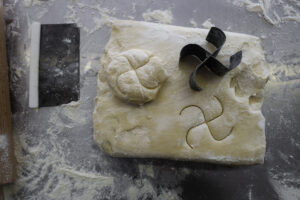 Un pezzo di impasto con sopra la forma di un panino e lo stampo a forma di svastica