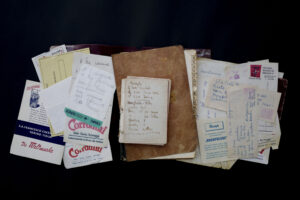 Un ricettario con fogli sparsi su una superficie nera.